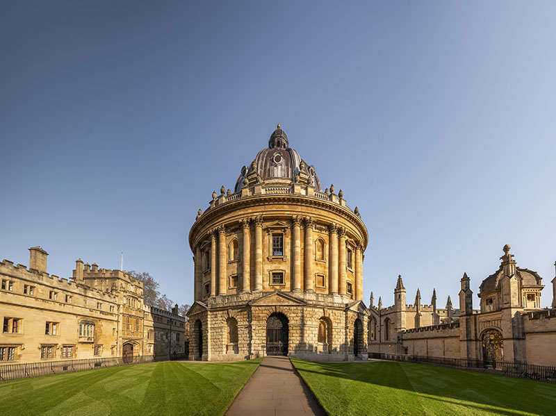 A wide view of the Radcliffe Camera and surrounding buildings on a bright and sunny day