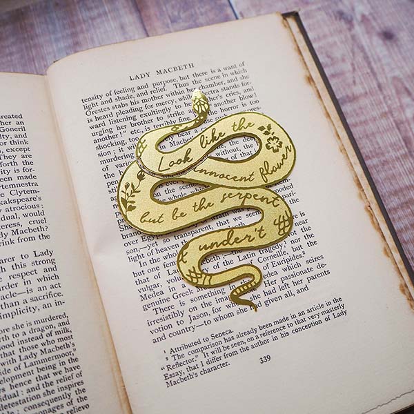 A golden bookmark engraved with a quotation laid on top of a book