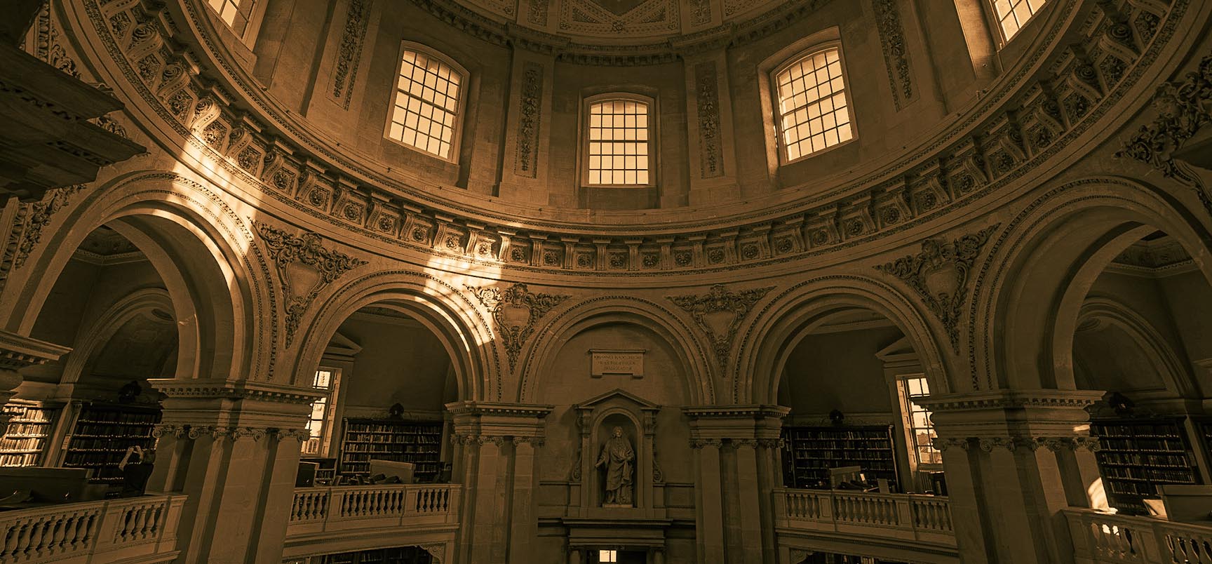 The circular interior of the Radcliffe Camera in low light, with sunlight falling from the windows