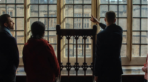 Image of 3 people stood in front of a window with one pointing out of the window