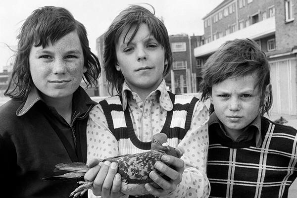 Black-and-white photograph of three children and a pigeon