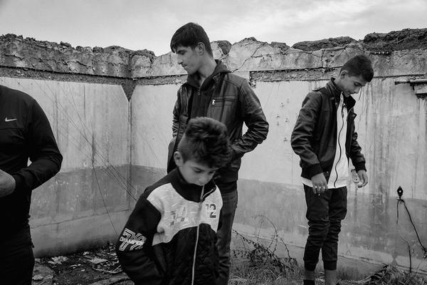 A black and white photo of four young and teenage boys standing in the ruins of a building