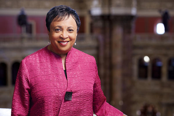 An African American woman with short black hair in a fuchsia pink coat