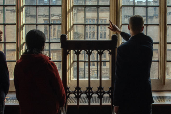 Image of 3 people stood in front of a window with one pointing out of the window