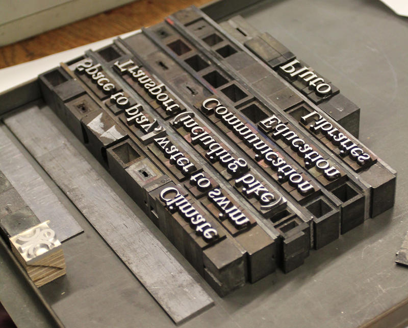 A photograph of letterpress typefaces - the letters read back to front on grey metal