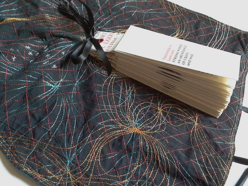 A pamphlet of handwritten text lies on top of a colourful fabric backing