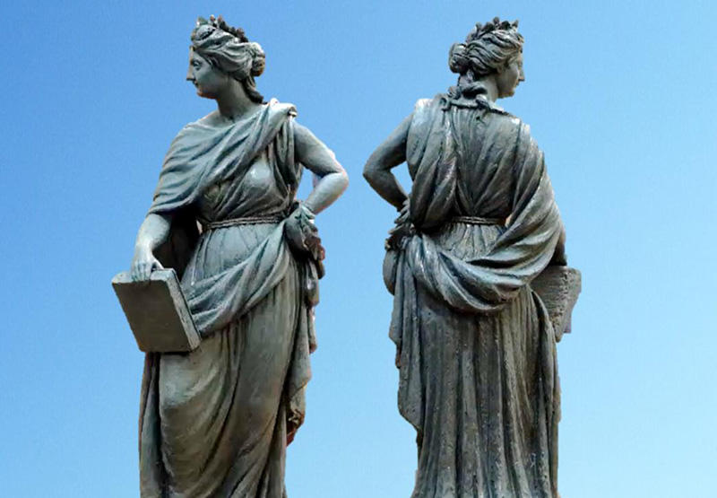 A front and rear view of a status of a woman wearing a toga and a laurel wreath, and carrying a book