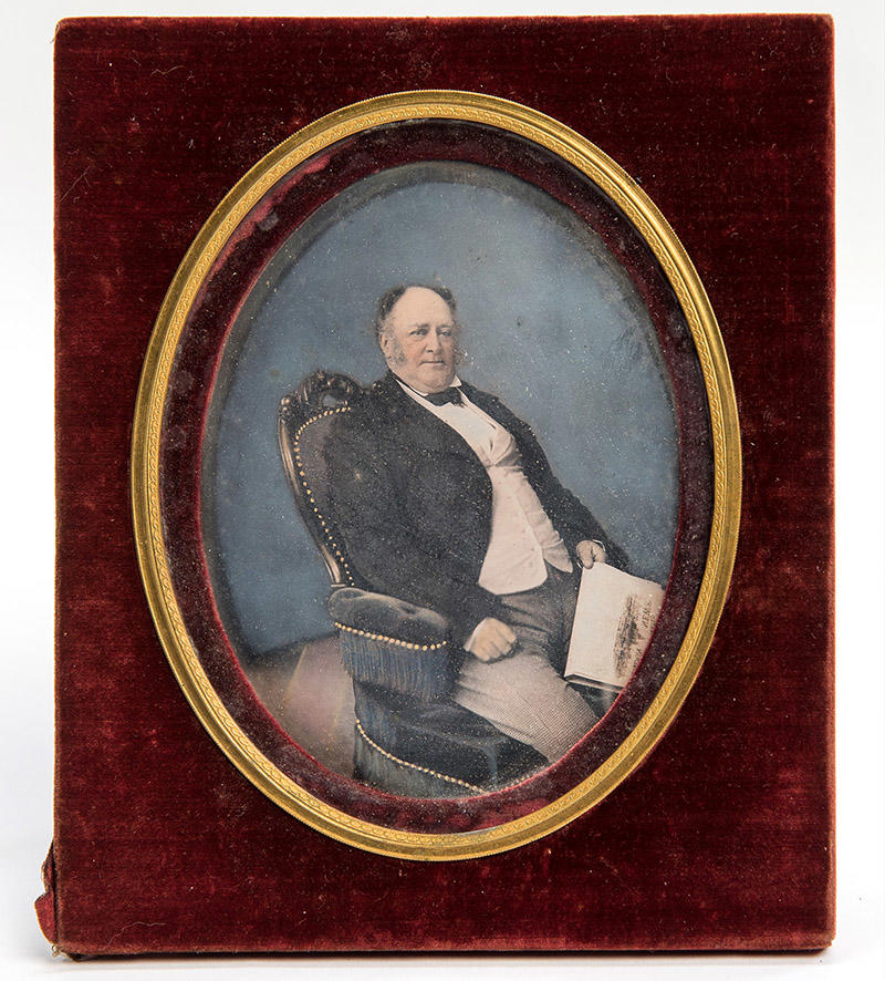 A daguerrotype of a man sitting in an armchair holding a newspaper