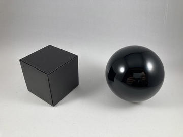 A matte dark grey cube next to a shiny dark grey sphere