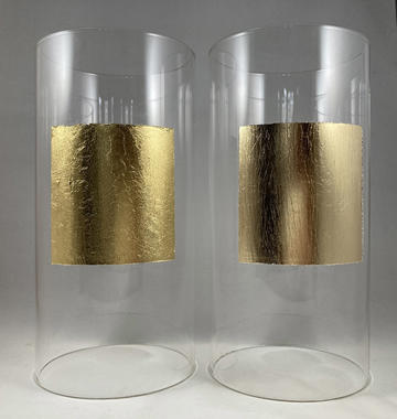 Two plastic cylinders next to each other - each has a square of gold-looking material on it