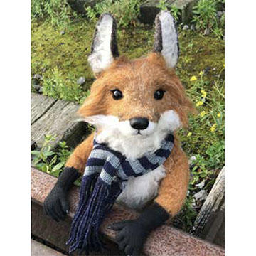 A fluffy stuffed puppet of a fox is looking at the camera